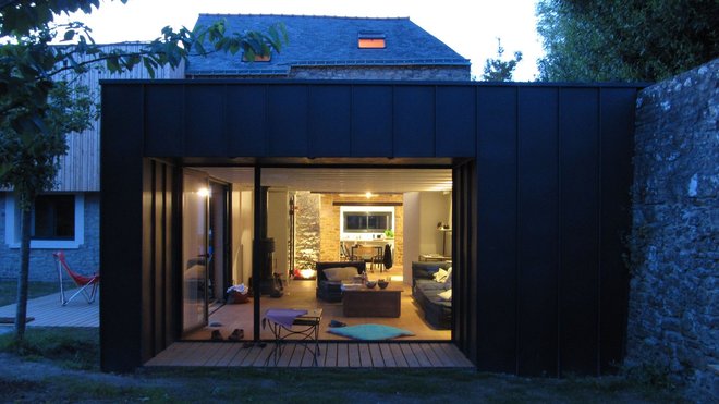Le salon s’ouvre sur le jardin par une large baie cadrant la vue et protégé du soleil estival par un débord de toiture. Le salon s’ouvre sur le jardin par une large baie cadrant la vue et protégé du soleil estival par un débord de toiture.
