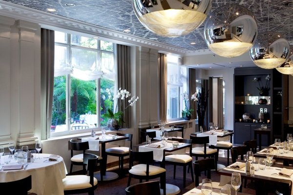 Vue sur un jardin clos, calme absolu pour une table qui se prête élégamment à des déjeuners d'affaires ou dîners feutrés.