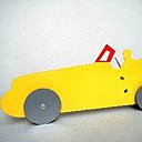 "BIGRACER" jaune rutilant, pare brise rouge et roues en acier, un conducteur fier de son bolide.