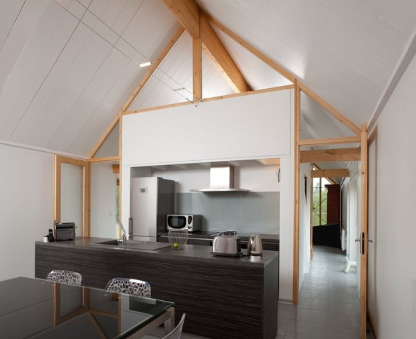 Une cuisine adossée à l’espace salon, avec une communication de part et d’autre de la grande pièce à vivre.