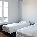 Dans l’une des chambres, une rosace en staff cohabite avec une suspension lumineuse contemporaine au dessus de lits jumeaux.