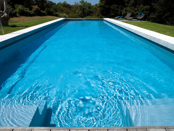 Bordée de béton dans un style résolument contemporain, la longue piscine courre sur 15 mètres de long pour seulement 4,5 mètres de large. Effet bassin de nage garanti !