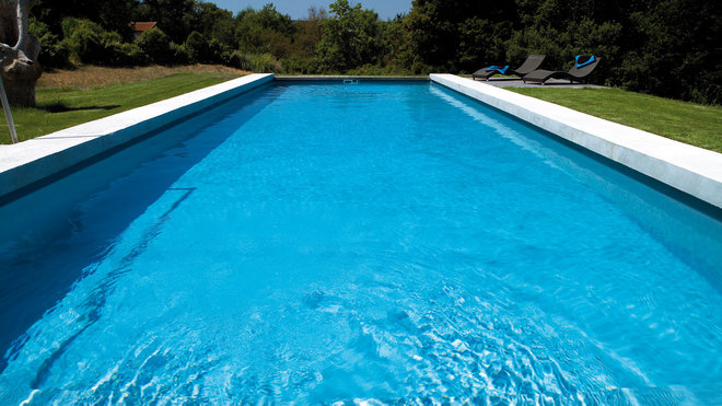 Bordée de béton dans un style résolument contemporain, la longue piscine courre sur 15 mètres de long pour seulement 4,5 mètres de large. Effet bassin de nage garanti !