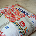 Coussin à l'aspect scandinave résolument moderne, composé de pièces de tissus brodés, découpées dans des nappes anciennes.