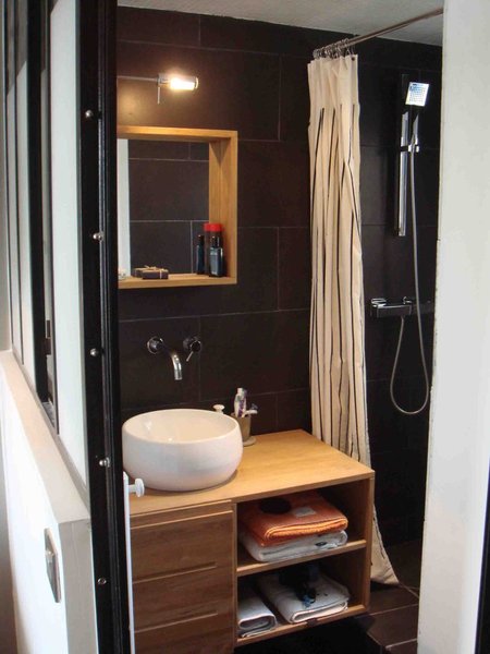 Une salle de bains miniature mais qui offre une douche carrelée de 0,75 m x 1, 25 m et des rangements en teck massif.