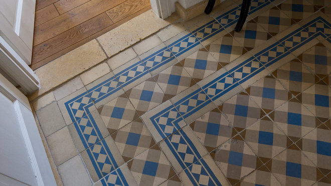 Déniché chez un récupérateur autrichien, le carrelage de l’entrée forme un élégant dessin bordé d’une frise, donnant l'impression que le sol a toujours été là.