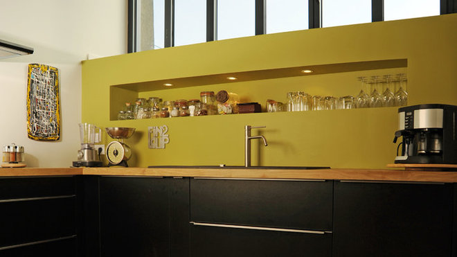 Sous la verrière, un aménagement en verre teinté anis, intégrant un système d’éclairage dans une niche, a permis de rattraper les différences de niveau du mur qui s’évasait vers le bas.