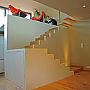 Monté sur une estrade, un podium réalisé en ossature bois recouverte de plaques de plâtre et de parquet accueille un petit coin détente lumineux.