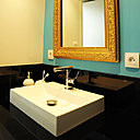 Dans la salle de bains, un miroir chiné et redoré contraste avec un mur turquoise, la blancheur d’un lavabo en acrylique et la modernité d’un meuble sous vaque laqué noir, réalisé sur mesure.