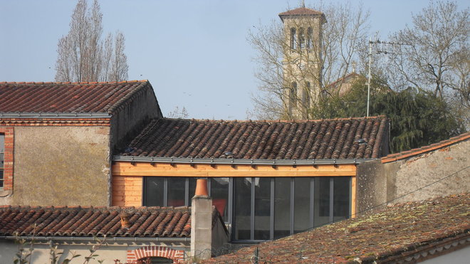L’atelier rénové de l’extérieur, avec sa baie vitrée encadré d’un bardage bois, s’intègre parfaitement dans la trame urbaine de cette petite ville de province.