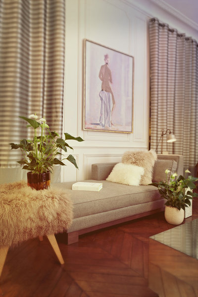 Des anthuriums blancs, accordés aux tons neutres de la méridienne, des coussins et du tabouret en fourrure, embellissent le coin lecture.