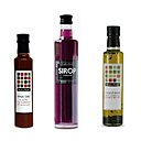 Flacons rares d'épicerie fine: vinaigres élégants, sirop de violette et huile d'olive aux 2 basilics et tomates séchées.