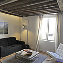 Au mur, un triptyque de photos de paysages ramenées de voyage, réalisées par le propriétaire et tirées sur plaques métalliques. Canapé Caravane.