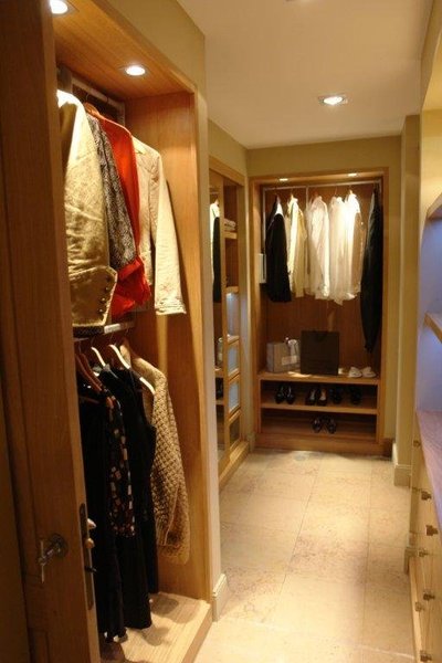 Le dressing s’inscrit dans une essence de bois massive, où les vêtements sont mis en valeur, pour offrir un rangement fonctionnel.