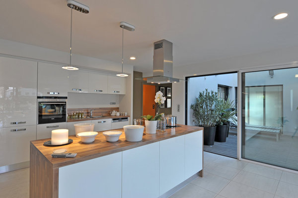 Une vaste cuisine ouverte sur une grande pièce à vivre et en liaison directe avec un patio, une zone tampon qui régule la température de la maison.