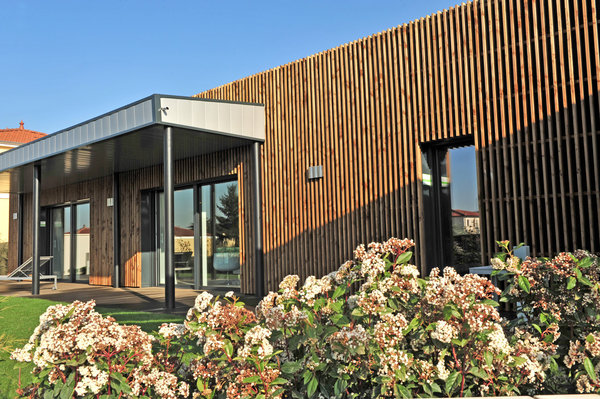 La maison est recouverte d’un bardage bois ajouré qui s’ajoute aux enduits extérieurs organiques bi-ton, de l’autre côté du bâtiment.