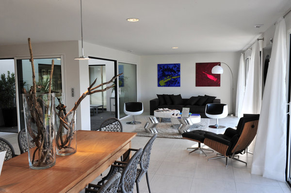 Un salon et une salle à manger qui s’articulent autour du patio et s’ouvrent sur une terrasse couverte, pour former une lumineuse pièce à vivre.