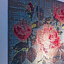 Panneau mural brodé au point de croix d'une rose traditionnelle pixellisée.