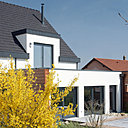 Pour conserver une enveloppe thermique sans rupture, l’ossature en bois est renforcée grâce à une alliance avec l’aluminium. Les larges baies vitrées sont largement ouvertes vers l’extérieur, avec une vue imprenable sur le jardin.