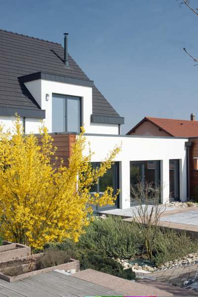 Pour conserver une enveloppe thermique sans rupture, l’ossature en bois est renforcée grâce à une alliance avec l’aluminium. Les larges baies vitrées sont largement ouvertes vers l’extérieur, avec une vue imprenable sur le jardin.