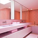 Corian pour le plan vasque et calepinage de pâtes de verre roses en losange pour la confortable salle de bains à la lumière zénithale.