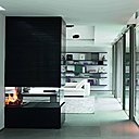 Une large et sculpturale cheminée décentrée, habillée de pierre striée sépare deux espaces de réception