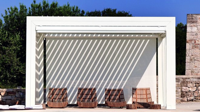 Schelter est une pergola en aluminium blanc. La couverture automatique télécommandée est réalisée en lames d’aluminium orientables, de 0° à 130° environ. En cas de pluie, la fermeture garantit un abri parfaitement hermétique.