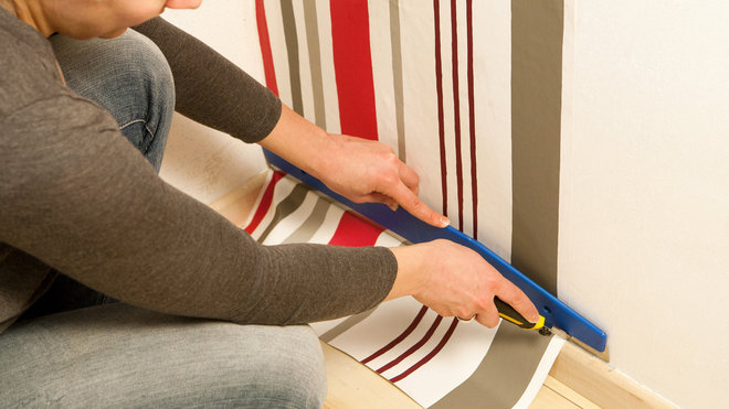 Je bloque le papier en bas des plinthes et je découpe le papier au ras avec un cutter.