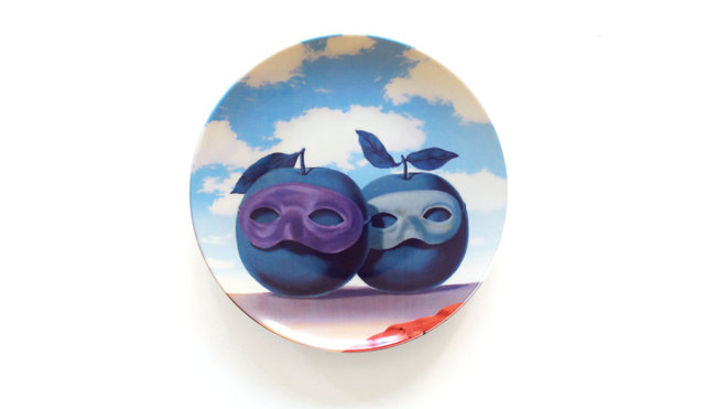 En porcelaine de Limoges, Ligne Blanche s’inspire des œuvres de Magritte, comme dessein pour une série d’assiettes. « Le domaine enchanté VII » reprend le thème d’une identité faussé avec ces deux pommes masquées.