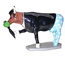 Cette statuette d’Artedeum rend hommage à la Cow Parade, avec cette vache grimée par l’inspiration Magritte. Elle reprend les différents composants de son œuvre : avec la pomme, le ciel nuageux et le chapeau melon.