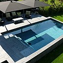 Dans le prolongement direct de la terrasse, cette piscine rectangulaire en béton armé s’inscrit comme une pièce à vivre. L’élégance du carrelage gris anthracite qui habille les parois, combiné aux plages et margelles en granit ,apporte une esthétique irréprochable. Architecte Lode Architecture. Réalisation Carré Bleu Concept & Création à Linas.