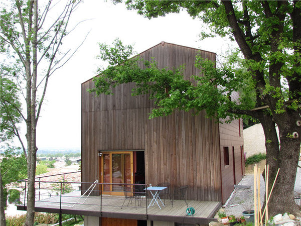 Si la construction n’a pu être entièrement réalisée en bois à cause de contraintes régionales, les architectes ont offert un compromis avec une façade en lame pour les pignons ouest et est de la maison.