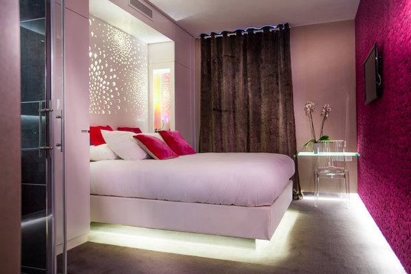 Dans la chambre « Dahlia » rose, le mur est tapissé de velours capitonné, comme une loge de salle de spectacle type cabaret. L’ambiance rétro est ravivée par le jeu des reflets de lumières sur des matières réactives comme le plexi.
