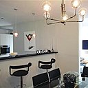 La cuisine semi-ouverte avec son bar et à été conservée. Elle dessine désormais un espace graphique en noir et blanc. Dans la salle à manger, table Jérôme Guimier. Lustre et chaises, Bô.