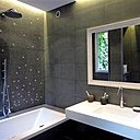 Pour les parents, une salle de bains métamorphosée avec baignoire intégrant un système de chromothérapie, un plan vasque en Coral (proche du Corian®) et une mosaïque de carrelage au mur (Réalisation Bain Douch Création).