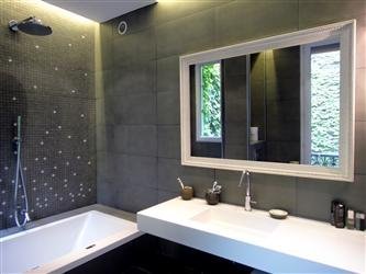 Pour les parents, une salle de bains métamorphosée avec baignoire intégrant un système de chromothérapie, un plan vasque en Coral (proche du Corian®) et une mosaïque de carrelage au mur (Réalisation Bain Douch Création).