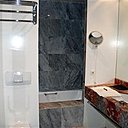 Avant, pour les parents, une petite salle de bains, au décor chargé, habillée par le mariage maladroit de deux marbres.