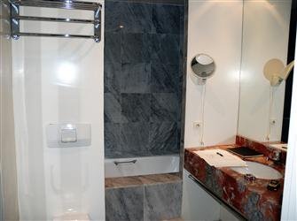 Avant, pour les parents, une petite salle de bains, au décor chargé, habillée par le mariage maladroit de deux marbres.