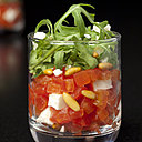 Tomate et fêta, un grand classique revu et corrigé version tartare sur lit de feuilles de roquette et pignons torréfiés.