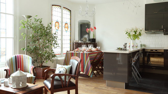 Après, une véritable pièce à vivre intégrant une cuisine. L’espace n’a pas perdu son cachet ancien avec les  détails en vitrail des fenêtres conservées, qui contrastent avec l’éclairage en lignes câblées. Le carrelage composé de carreaux façon métro apporte une touche de style industriel, à l’espace cuisine.