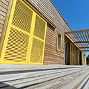 Élégance des volets jaunes répondant au bois naturel pour la sélection du Jury: maison "Ossard", catégorie Logements individuels plus de 120 m².