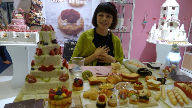 Rio Fukuda devant sa table de fabrication au salon l'Aiguille en Fête.