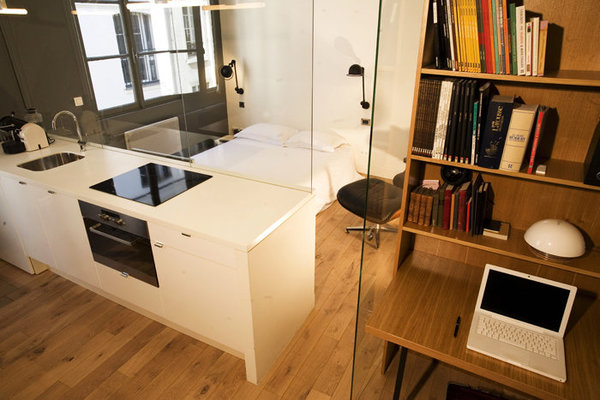 Un plan en Corian®  surmonte  les meubles de cuisine, aménagés en séparation de pièce, qui camouflent le lit de la chambre. La pièce à vivre comporte un petit coin bureau.