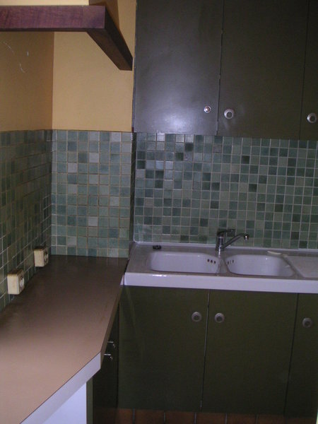 L’ancienne cuisine, au carrelage similaire à celui de la salle de bains, et aux couleurs typiques de la fin des années 1970.