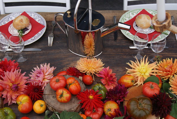 Élégante association de dahlias et tomates composant un décor de table original sur la grande table d'hôtes du Bar à Tomates de la Bourdaisière.