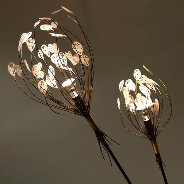 Lampe photoluminescente, en acier et dentelle de Calais et fil photoluminescent, qui continue de briller dans la nuit, telle un arbuste à lucioles. Elle est le fruit de la collaboration entre l’un des derniers spécialistes français à fabriquer la dentelle de Calais, les entreprises Codentel, les tissages de Lys, une référence dans le domaine des tissages jacquard et un bureau de style dédié au textile.  Création TAND’M, 2012.