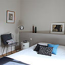 Pour redimensionner, rééquilibrer la géométrie de cette chambre et rattraper le mur en biais, un dosseret a été pratiqué en tête de lit. Ce muret camoufle les écoulements détournés pour créer une nouvelle salle de bains et une cuisine dans la pièce à vivre.