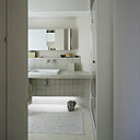 Toute de gris vêtue, salle de bains nappée d’un sol en résine cirée qui imite le béton et carrelage en pâte de verre (Leroy Merlin). Au sol, sculpture en pierre de Jean-François Nansot.