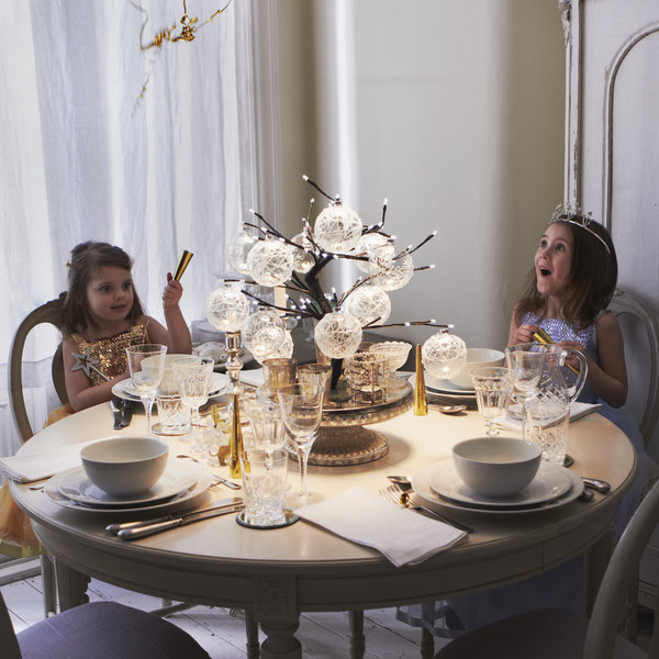 Un centre de table lumineux composé d'un mini arbre décoré de boules de verre gravées.