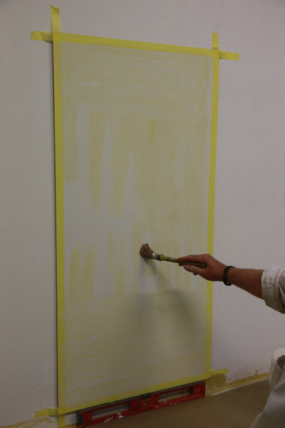 Etape 4 : Avec la brosse de pouce, appliquer le glacis à l’huile teinté sur l’ensemble de la surface à décorer. Appliquer dans le sens de la hauteur, de bas en haut et de droite à gauche, croiser en largeur de haut en bas, puis avec le spalter lisser dans le sens de la hauteur de bas en haut et de droite à gauche. Vous devez obtenir une surface tendue, homogène et d’un aspect assez lisse.